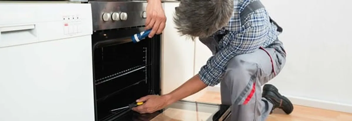 Oven repair technician inspecting and servicing an electric oven in Sioux Falls, SD