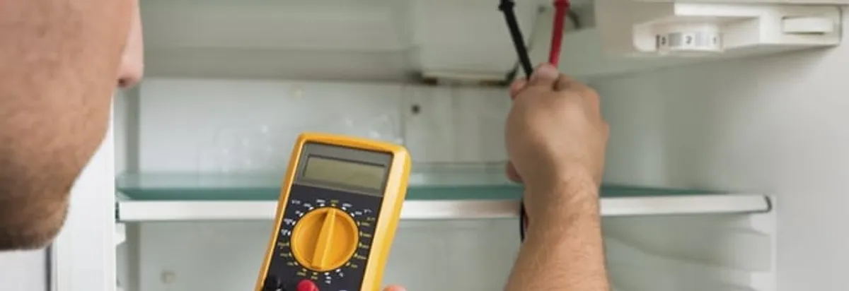 Refrigerator repair technician testing electrical components with a multimeter in Sioux Falls, SD