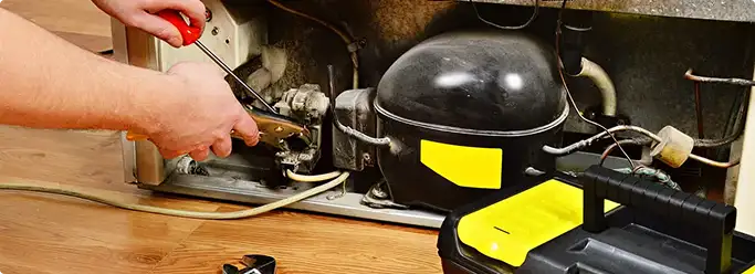 Refrigerator repair technician fixing the compressor and wiring in Sioux Falls, SD
